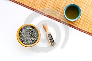 Chinese tea concept. Tea ceremony. Dry tea leaves in bowl and wooden scoop near cup of tea on white background and