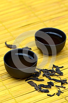 Chinese tea cups and wild puerh on yellow mat