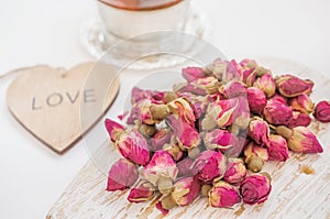 Chinese Tea with pink buds . Tea rose buds made from real rose buds, plucked young and then dried. A Cup of tea and a