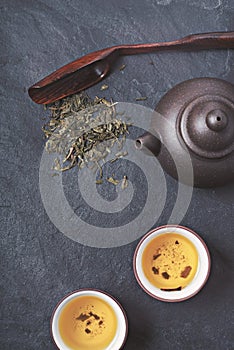 Chinese teapot and bowl with green tea on the stone background vertical