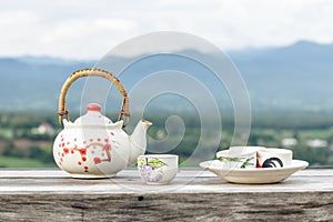 Chinese teapot and teacups on wood table and mountain landscape