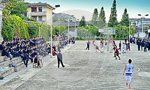 Chinese teenagers playing a basketball game in the high school.