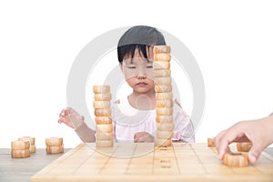 Chinese three-year-old child stacks Chinese chess pieces high on the chessboard