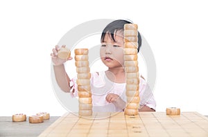 Chinese three-year-old child stacks Chinese chess pieces high on the chessboard