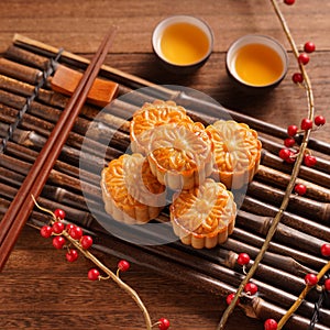 Chinese traditional pastry Moon cake Mooncake with tea cups on bamboo serving tray on wooden background for Mid-Autumn Festival,