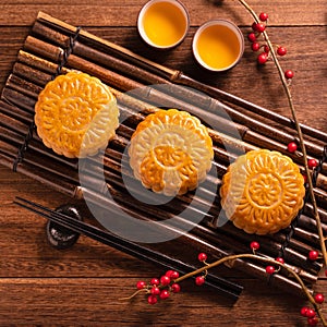 Chinese traditional pastry Moon cake Mooncake with tea cups on bamboo serving tray on wooden background for Mid-Autumn Festival,