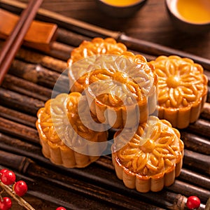 Chinese traditional pastry Moon cake Mooncake with tea cups on bamboo servingwarning tray on wooden background for Mid-Autumn