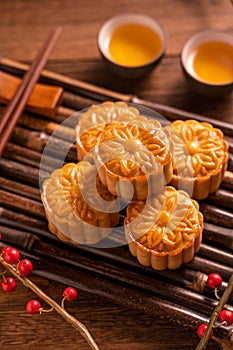 Chinese traditional pastry Moon cake Mooncake with tea cups on bamboo servingwarning tray on wooden background for Mid-Autumn