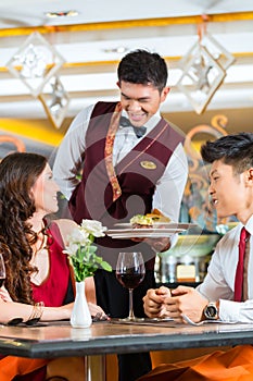 Chinese waiter serving dinner in elegant restaurant or Hotel