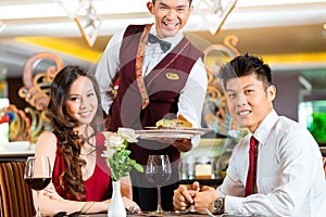 Chinese waiter serving dinner in elegant restaurant or Hotel