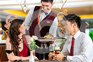 Chinese waiter serving dinner in elegant restaurant or Hotel photo