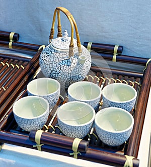 Chinese white teapot and teacups on the wooden trivet