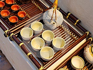 Chinese white teapot and teacups on the wooden trivet