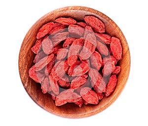 Chinese wolfberries in wooden bowl, isolated on white background. Heap of dried goji berry. Top view.