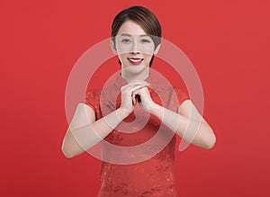 Chinese woman in a cheongsam dress with a congratulations gesture