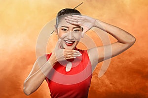 Chinese woman in cheongsam dress framing her face with hand