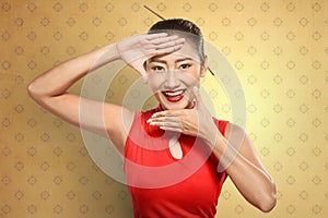 Chinese woman in cheongsam dress framing her face with hand