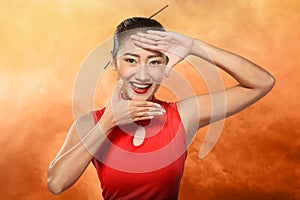 Chinese woman in cheongsam dress framing her face with hand photo