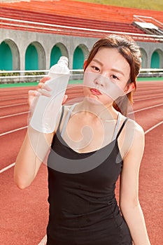 Chinese woman drinking water after jogging