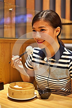 Chinese Woman eating Steamed dumpling in restaurant