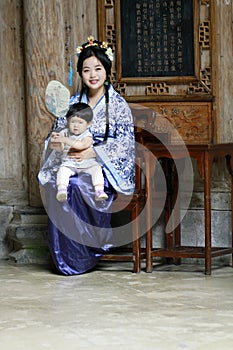 Chinese woman in Hanfu dress, hold her baby in cheongsam