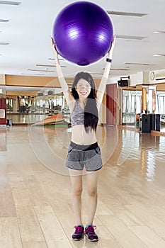 Chinese woman lifting fitness ball at gym center