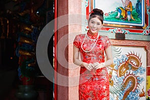 Chinese woman in a red cheongsam dress pay homage to Chinese god at shrine. Concept to celebrate Chinese New Year photo
