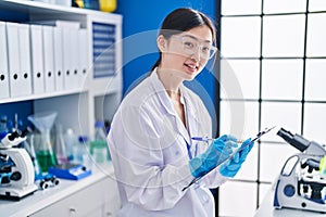 Chinese woman scientist writing on document at laboratory