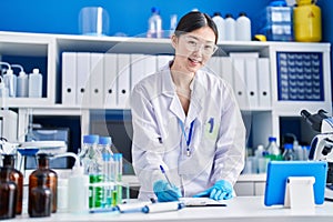 Chinese woman scientist writing on document using touchpad at laboratory