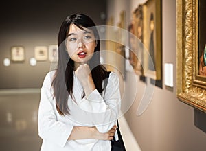 Chinese woman standing in art museum near the painting