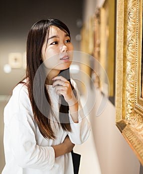Chinese woman standing in art museum near the painting