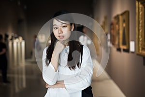 Chinese woman standing in art museum near the painting