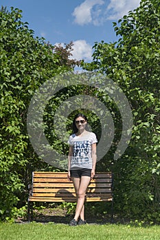 Chinese woman standing near a wooden bench