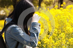 Chinese woman taking pictures of yellow flowers