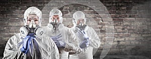 Chinese Woman and Team Behind In Hazmat Suites, Gas Masks and Goggles Against Brick Wall photo