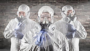 Chinese Woman and Team Behind In Hazmat Suits, Gas Masks and Goggles Against Brick Wall