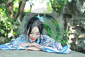 Chinese woman in traditional Blue and white Hanfu dress Climb over the stone table