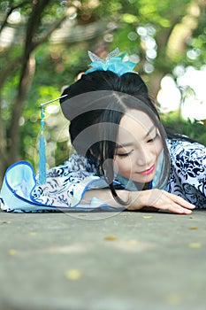 Chinese woman in traditional Blue and white Hanfu dress Climb over the stone table