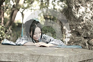 Chinese woman in traditional Blue and white Hanfu dress Climb over the stone table