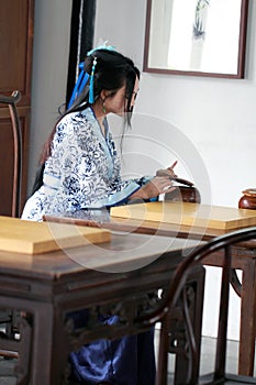 Chinese woman in traditional Blue and white Hanfu dress play the game of go