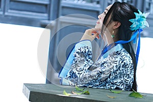 Chinese woman in traditional Blue and white Hanfu dress Sit on the stone bench