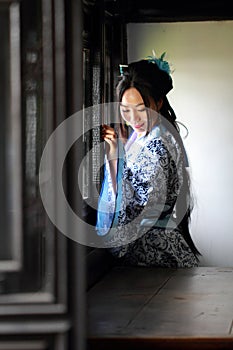 Chinese woman in traditional Blue and white Hanfu dress Stand behind the window