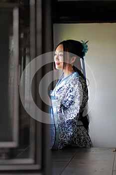 Chinese woman in traditional Blue and white Hanfu dress Stand behind the window