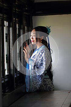 Chinese woman in traditional Blue and white Hanfu dress Stand behind the window