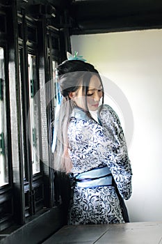 Chinese woman in traditional Blue and white Hanfu dress Stand behind the window