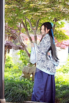 Chinese woman in traditional Blue and white Hanfu dress Stand under the maple tree