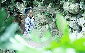 Chinese woman in traditional Blue and white Hanfu dress Standing in front of the rockery