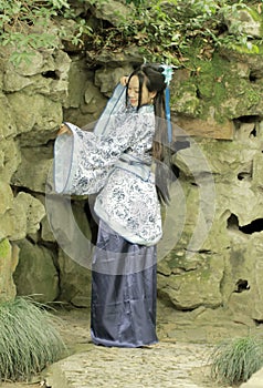 Chinese woman in traditional Blue and white Hanfu dress Standing in front of the rockery