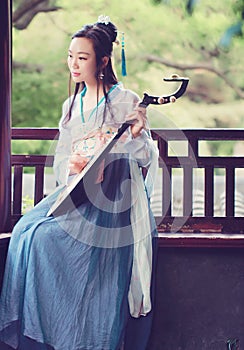 Chinese woman in traditional Hanfu dress,play traditional instrument of pipa