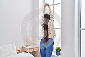 Chinese woman waking up stretching arms at bedroom